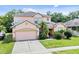 Charming two-story home with a well-manicured lawn and attached two-car garage at 2165 The Oaks Blvd, Kissimmee, FL 34746