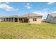 The grassy backyard has a covered patio, with additional homes in the distance at 2658 Meadowedge Loop, St Cloud, FL 34772