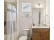 Bright bathroom with a light wood vanity, white countertop, a framed mirror, and white and blue shower curtain at 2658 Meadowedge Loop, St Cloud, FL 34772