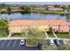 Scenic aerial view of townhomes by a tranquil lake, surrounded by lush greenery and ample parking at 3055 Yellow Lantana Ln, Kissimmee, FL 34747