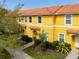 Bright yellow townhome featuring a red tile roof, well-maintained landscaping, and a welcoming entryway at 3055 Yellow Lantana Ln, Kissimmee, FL 34747