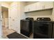 A laundry room with black washer and dryer, white cabinets, and wood-look tile flooring at 3262 Hanging Tide St, Winter Garden, FL 34787