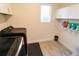 Well-lit laundry room with black washer and dryer, white cabinets, and wood-look tile flooring at 3262 Hanging Tide St, Winter Garden, FL 34787