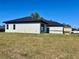Side view of a single story stucco home with black trim, a dark roof, and a well-maintained lawn at 4491 Sw 151 St, Ocala, FL 34473
