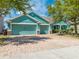 Charming teal house with a three-car garage and brick-paved driveway offering curb appeal at 4740 Cypress Forest Ln, St Cloud, FL 34772
