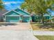 Teal home featuring a three-car garage, brick driveway, and well-maintained landscaping at 4740 Cypress Forest Ln, St Cloud, FL 34772