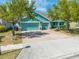 Inviting home featuring a teal exterior, three-car garage, brick driveway, and well-maintained landscaping at 4740 Cypress Forest Ln, St Cloud, FL 34772