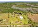 Aerial perspective reveals the property's home, shed, and pond amidst a verdant landscape, bordered by dense woodland at 5801 N Kenansville Rd, St Cloud, FL 34773