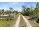 Private driveway marked with a gate, leading through a lush landscape with mature trees, promising seclusion at 5801 N Kenansville Rd, St Cloud, FL 34773