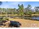 Idyllic view featuring a pond with lily pads, a rustic dock, and a bench overlooking the tranquil water at 5801 N Kenansville Rd, St Cloud, FL 34773