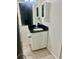 Bathroom featuring vanity with black granite countertop and white cabinets, and decorative mirror at 731 Wyman Ct # 731-A, Orlando, FL 32809