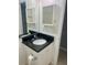 Bathroom featuring vanity with black granite countertop and white cabinets, and decorative mirror at 731 Wyman Ct # 731-A, Orlando, FL 32809