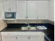 Galley style kitchen features white cabinets, modern microwave and black granite countertops at 731 Wyman Ct # 731-A, Orlando, FL 32809