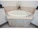 Close up of a soaking tub with tile surround in a bright bathroom at 10731 Belfry Cir, Orlando, FL 32832