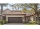 Charming townhome featuring a brick driveway, two-car garage, and stone accents, surrounded by lush greenery at 10731 Belfry Cir, Orlando, FL 32832