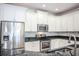 Modern kitchen featuring white cabinets, stainless steel appliances, and granite countertops at 10731 Belfry Cir, Orlando, FL 32832