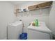 Clean laundry room with washer, dryer, wire shelving, and a blue laundry basket at 1107 Trappers Trail Loop, Davenport, FL 33896