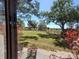 View of the backyard, featuring a grassy lawn and a fence bordering mature trees at 133 La Casa # 133, Lake Wales, FL 33898