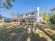 Expansive backyard view of home with screened porch, chimney, landscaping, and tree shadows at 1444 Pelican Bay Trl, Winter Park, FL 32792