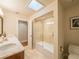 Bathroom showcasing a bathtub with glass enclosure, dual vanity, and natural light from a skylight at 1444 Pelican Bay Trl, Winter Park, FL 32792