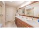 Bathroom with double sink vanity, large mirror, walk-in shower, and beige tile floors at 1444 Pelican Bay Trl, Winter Park, FL 32792