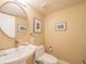 Tastefully decorated half bath features pedestal sink, toilet and framed decorative art at 1444 Pelican Bay Trl, Winter Park, FL 32792