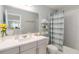 Well-lit bathroom with a vanity, a large mirror, and a shower with a blue and white curtain at 1565 Leaf Ln, Kissimmee, FL 34744