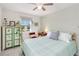 Bright bedroom with a bed dressed in mint green, complemented by a decorative cabinet and soft, natural lighting at 1565 Leaf Ln, Kissimmee, FL 34744