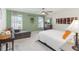 Well-lit bedroom with green walls, neutral carpet, ceiling fan, and a gray chaise lounge near the windows at 1565 Leaf Ln, Kissimmee, FL 34744