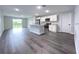Open-concept living space with stylish wood-look floors, a modern kitchen, and access to the backyard at 1706 3Rd Ave, Deland, FL 32724