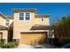 Two story tan home featuring a two car garage, manicured landscaping, and a stone facade on the bottom of the house at 17459 Chateau Pine Way, Clermont, FL 34711
