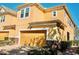 Two story tan home featuring a two car garage, manicured landscaping, and a stone facade on the bottom of the house at 17459 Chateau Pine Way, Clermont, FL 34711