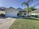 Well-maintained home with a two-car garage, lush front lawn, and mature palm trees, showcasing curb appeal at 2316 Paulette Dr, Haines City, FL 33844