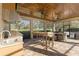 Covered outdoor kitchen with stainless steel appliances, bar seating, and serene views of the property at 2515 Ridgewind Way, Windermere, FL 34786