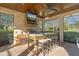 Outdoor kitchen with bar seating, grill, and wood ceiling at 2515 Ridgewind Way, Windermere, FL 34786