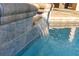 A close-up of a tiled water feature spilling into the pool adds an elegant and tranquil element to the outdoor space at 2515 Ridgewind Way, Windermere, FL 34786