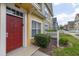 Close up of a colorful townhome featuring a red front door, manicured landscaping and white trim at 2604 Lodi Cir # 103, Kissimmee, FL 34746