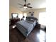 Spacious bedroom featuring dark wood floors, a tufted bed, a dresser, and natural light from the windows at 2678 Autumn Creek Cir, Kissimmee, FL 34747
