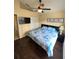 A cozy bedroom with a ceiling fan, dark wood floors, and a comfortable bed with a blue patterned comforter at 2678 Autumn Creek Cir, Kissimmee, FL 34747