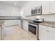 A modern kitchen featuring stainless steel appliances, stone counters and white cabinets at 2776 Tropical Lake Dr, Kissimmee, FL 34741