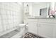 Bright bathroom with white cabinets, neutral-colored walls, and a shower with a white curtain at 2909 Theme St, Kissimmee, FL 34746