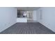 A wide shot of the living room, displaying the gray flooring and the bright and open kitchen with stainless appliances at 30376 Armenia Rd, Leesburg, FL 34748