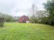 Exterior view of a large red barn in a grassy field with a cloudy sky at 3725 Blossom St, Kissimmee, FL 34746