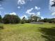Wide open yard featuring green grass, scattered trees, and prominently displayed solar panels on a sunny day at 3725 Blossom St, Kissimmee, FL 34746