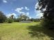 Open, green yard featuring scattered trees and a set of solar panels on a sunny day with scattered clouds at 3725 Blossom St, Kissimmee, FL 34746