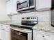 Modern kitchen features stainless steel appliances, granite counters, and white cabinets at 4105 Tropical Isle Blvd # 222, Kissimmee, FL 34741