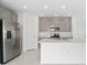 Bright kitchen with stainless steel appliances, island, and gray cabinets at 606 Bell Prairie Cir, Lake Wales, FL 33859