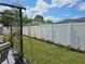 Backyard with white vinyl fence, green lawn, and landscaping on a sunny day at 633 Kangaroo Dr, Kissimmee, FL 34759