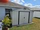 Exterior shed with a white color in the backyard, surrounded by green grass and a small garden at 633 Kangaroo Dr, Kissimmee, FL 34759