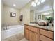 Bathroom with a soaking tub, granite countertops, and vanity mirrors at 802 Suffolk Pl, Davenport, FL 33896